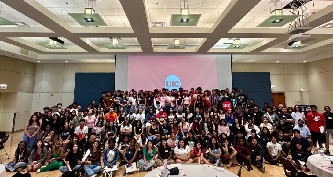 group of FLN cohort smiling in front of a projector with the UIC logo